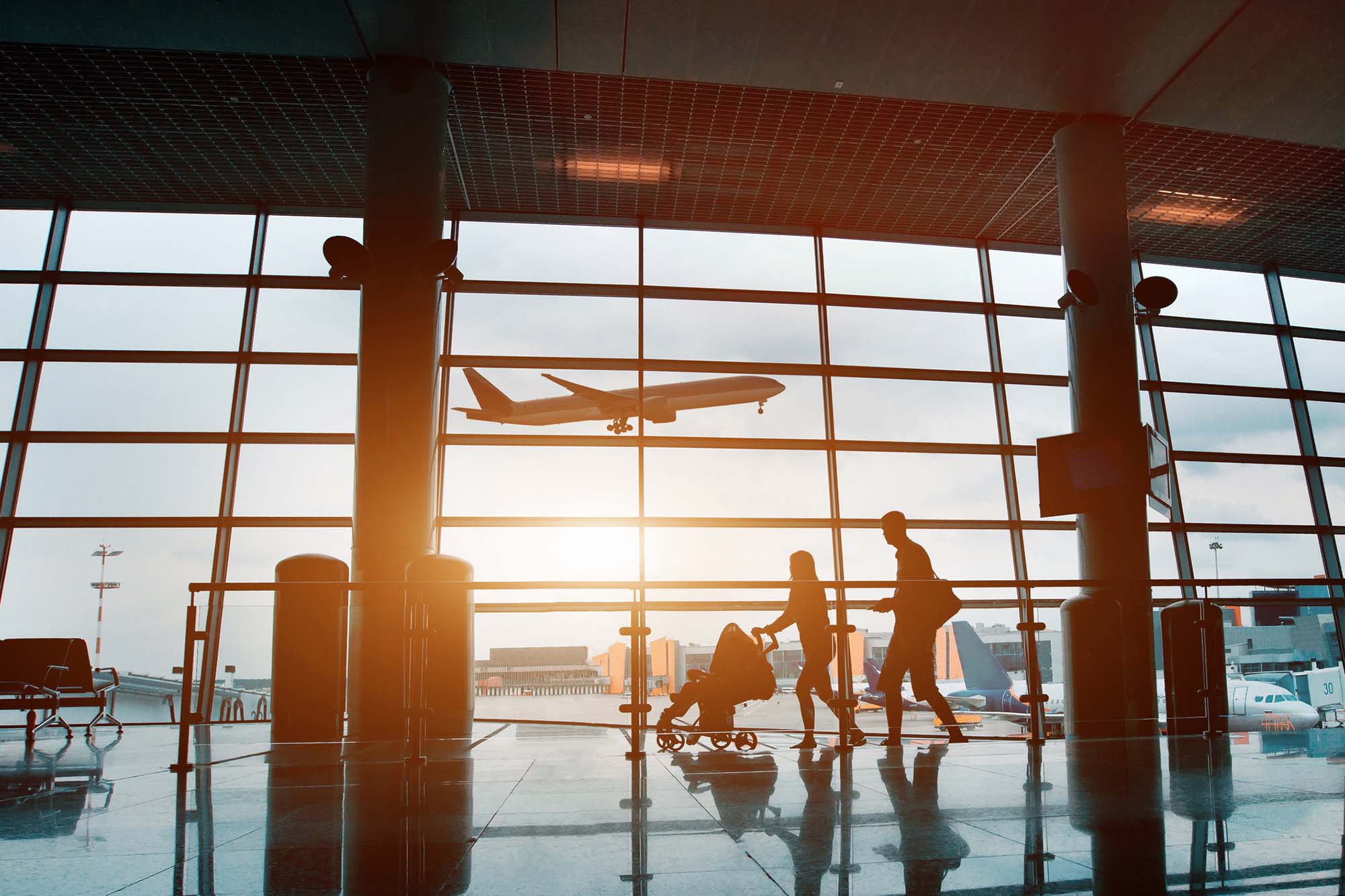 Family traveling with children, silhouette in airport. People in airport, silhouette of young family with baby traveling by plane
