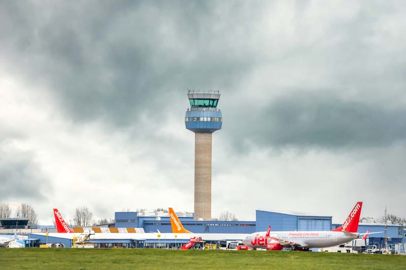 East Midlands Airport Kegworth Leicestershire radio air traffic Control tower and aircraft planes waiting depart modern terminal. East Midlands Airport Kegworth Nottingham 14. 4. 2021 radio air traffic Control tower and aircraft planes waiting to depart modern terminal runway with stormy cloud sky behind.