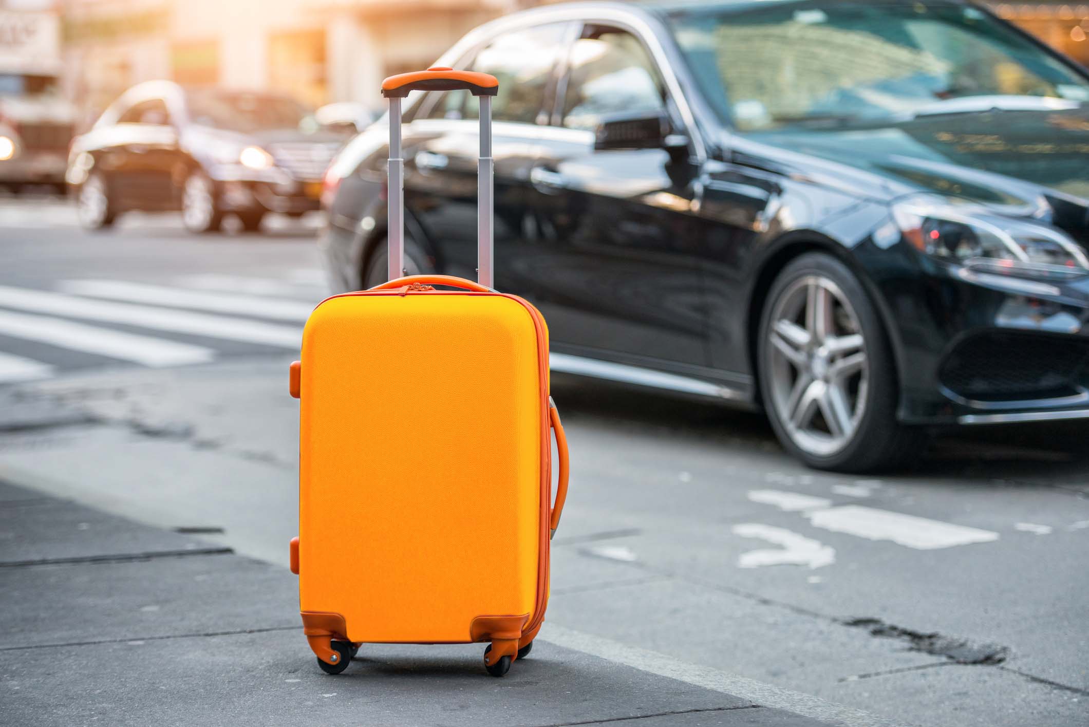 Orange suitcase in front of black taxi